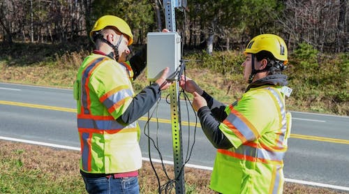 Virginia Tech Transportation Institute researchers (from left) Will Vaughn and Daniel Burdisso install part of the VTTI Smart Work Zone on a road sign. Photo by Jean Paul Talledo Vilela for Virginia Tech.